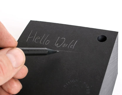 Detailaufnahme: Notizzettel Cube, Oberfläche mit handschriftlicher Notiz, Stift schreibt auf dem Block